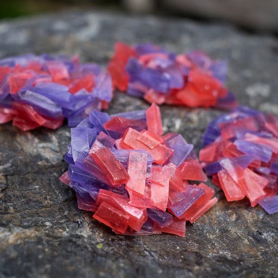 Red and purple crystal candy clusters (strawberry + blueberry) on stone; thin-slice pieces with clean, addictive crunch.