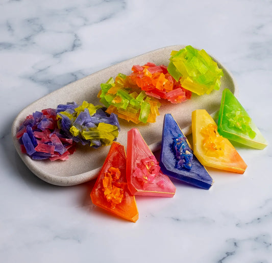 On stone background, a Long platter filled with five Japanese crystal candy clusters and five crystal candy clusters on a round marble table; thin-slice clusters with satisfying ASMR crunch.