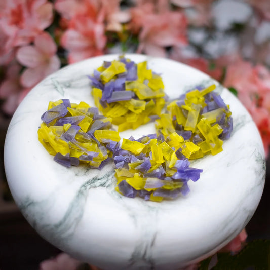 Purple and yellow crystal candy clusters on a white marble plate with flowers; pineapple + blueberry flavour, thin-cut for ASMR crunch.