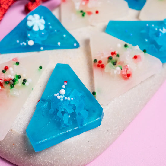 Zoom in a white and blue Japannese style crystal candy with sprinkles on a pink background.