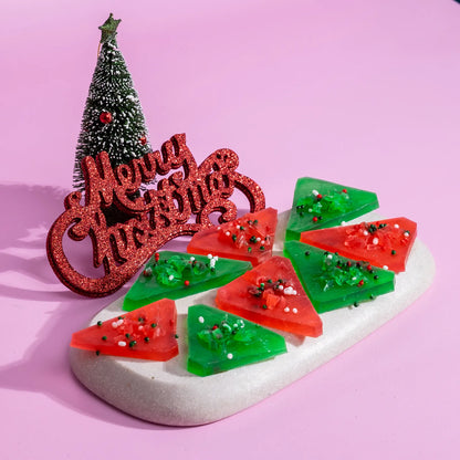 Decorative Christmas crystal candy with red and green crystal candy, 'Merry Christmas' sign, and small Christmas tree on a pink background.